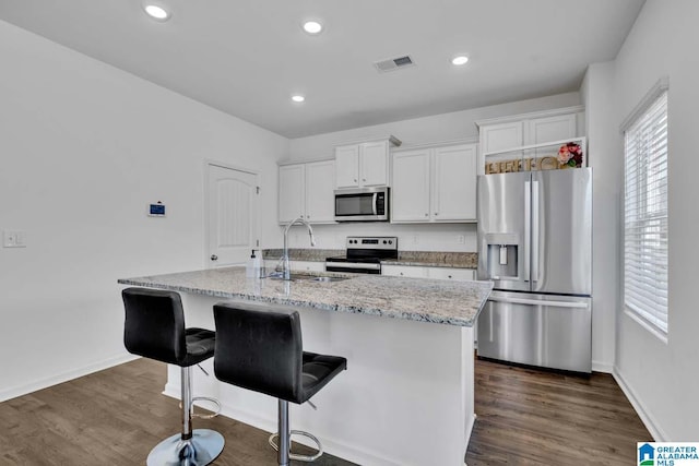 kitchen featuring appliances with stainless steel finishes, dark hardwood / wood-style flooring, sink, a center island with sink, and white cabinetry