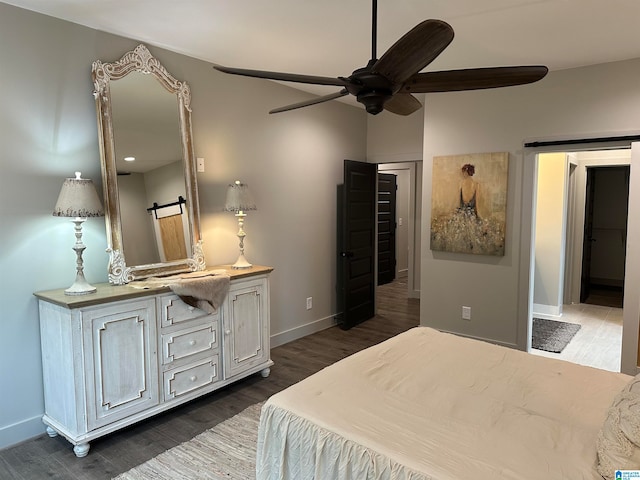 bedroom featuring dark hardwood / wood-style flooring, a barn door, and ceiling fan