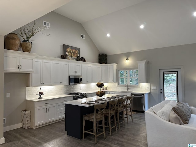 kitchen with a breakfast bar, sink, a kitchen island, stainless steel appliances, and white cabinets