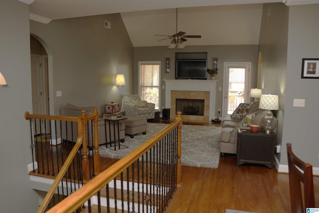 living room featuring wood-type flooring, ceiling fan, a wealth of natural light, and a tiled fireplace