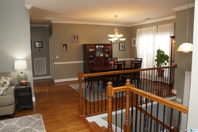 dining room with hardwood / wood-style flooring, a notable chandelier, and crown molding