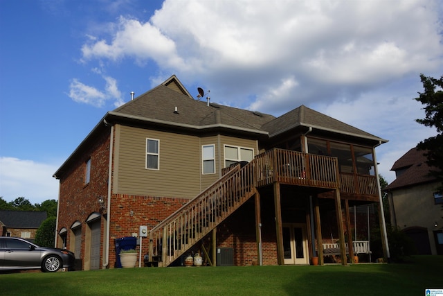 back of property with a lawn, a garage, central air condition unit, and a wooden deck