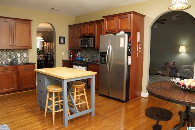 kitchen with decorative backsplash, stainless steel appliances, light hardwood / wood-style flooring, and a breakfast bar area