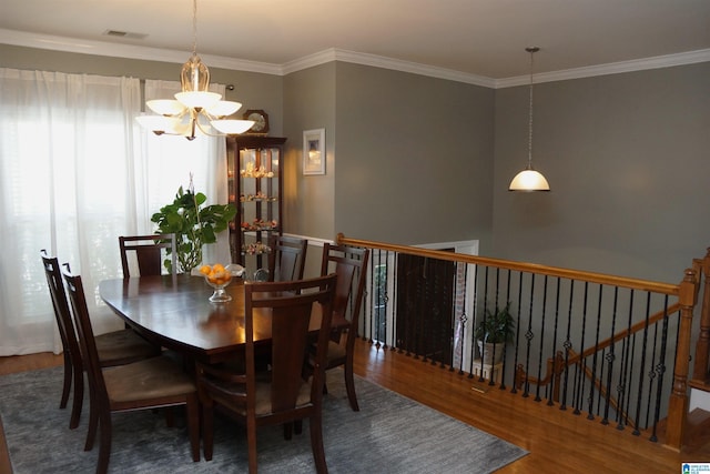 dining space featuring hardwood / wood-style floors, an inviting chandelier, and crown molding