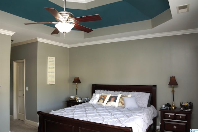 bedroom featuring a tray ceiling, ceiling fan, crown molding, and carpet floors