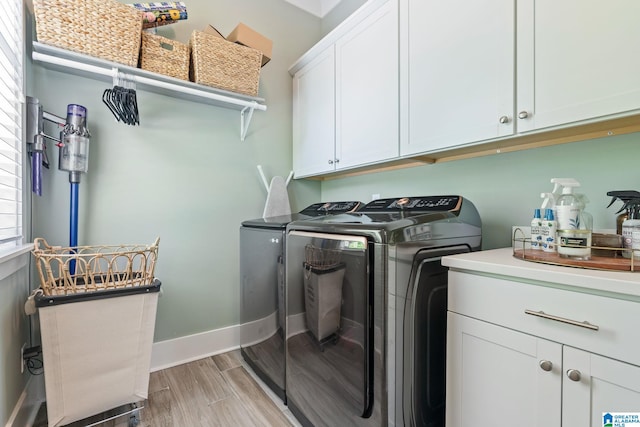 clothes washing area featuring independent washer and dryer, light hardwood / wood-style flooring, and cabinets