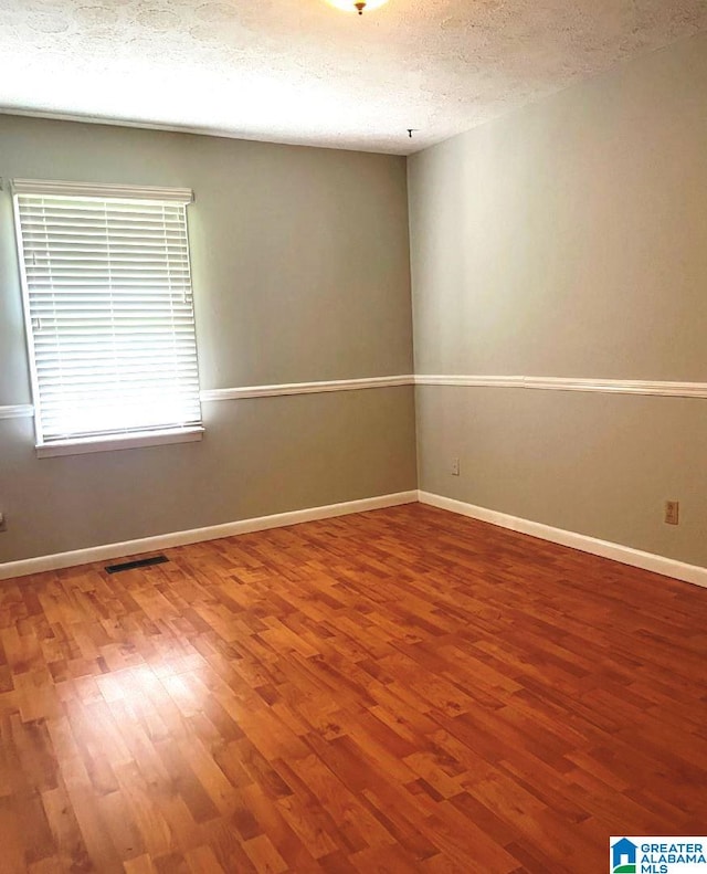 empty room featuring wood-type flooring and a textured ceiling