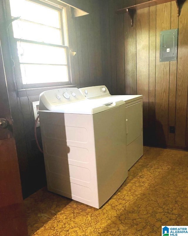 laundry area with washer and clothes dryer, wooden walls, and electric panel