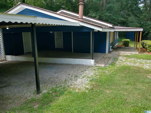 back of property with a carport and a lawn