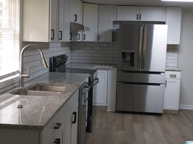 kitchen with light wood-type flooring, a sink, under cabinet range hood, white cabinetry, and stainless steel appliances