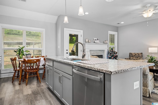 kitchen featuring sink, decorative light fixtures, stainless steel dishwasher, a center island with sink, and gray cabinetry