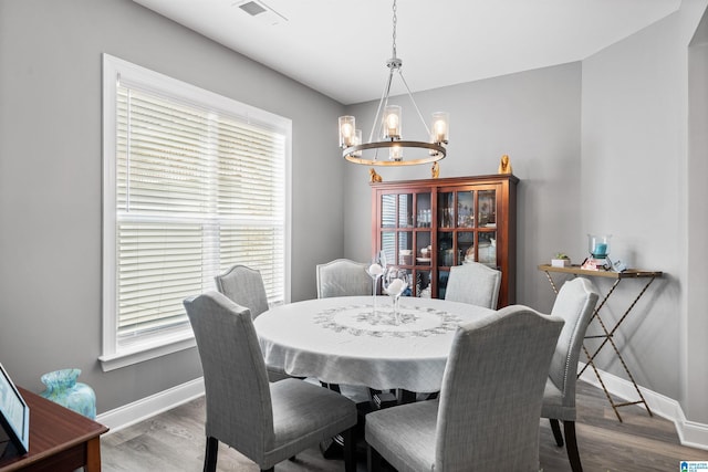 dining area with a healthy amount of sunlight, an inviting chandelier, and hardwood / wood-style flooring