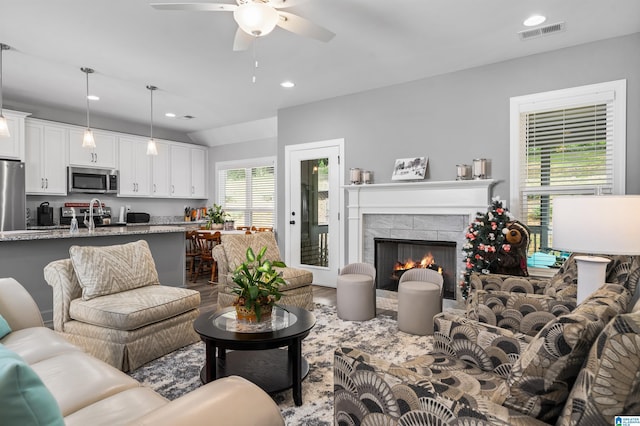 living room featuring a tile fireplace and ceiling fan