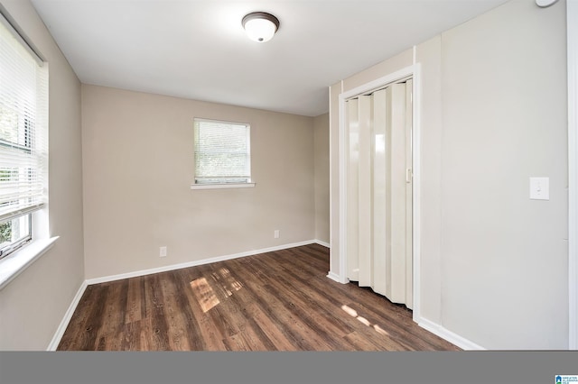 unfurnished bedroom featuring multiple windows, a closet, and dark wood-type flooring