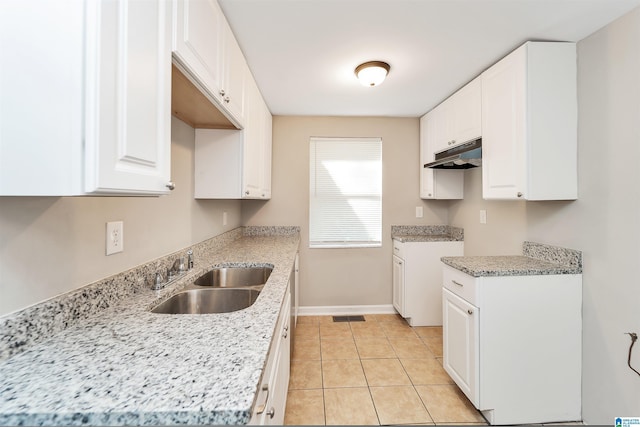 kitchen featuring light tile patterned flooring, light stone countertops, white cabinetry, and sink