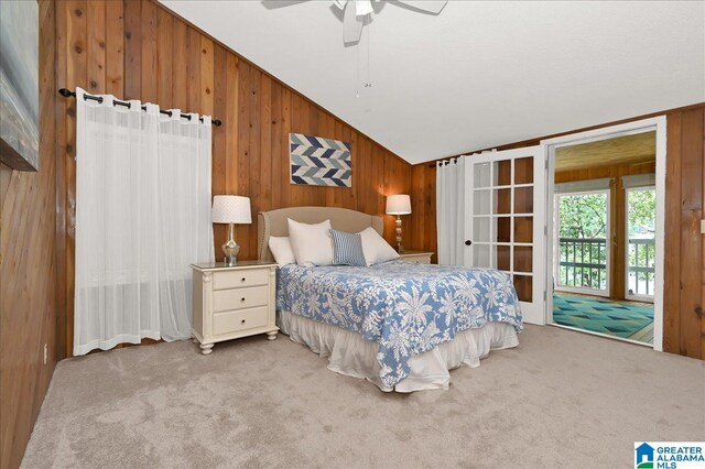 carpeted bedroom with wood walls, ceiling fan, and vaulted ceiling