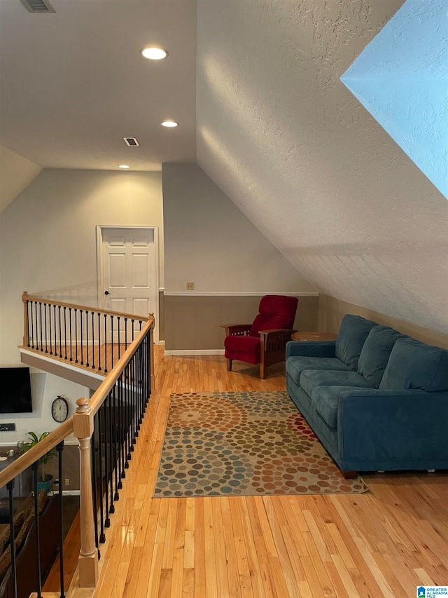 bonus room with wood-type flooring, a textured ceiling, and vaulted ceiling