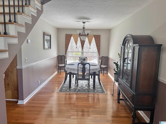 dining area with hardwood / wood-style flooring, a textured ceiling, and a notable chandelier