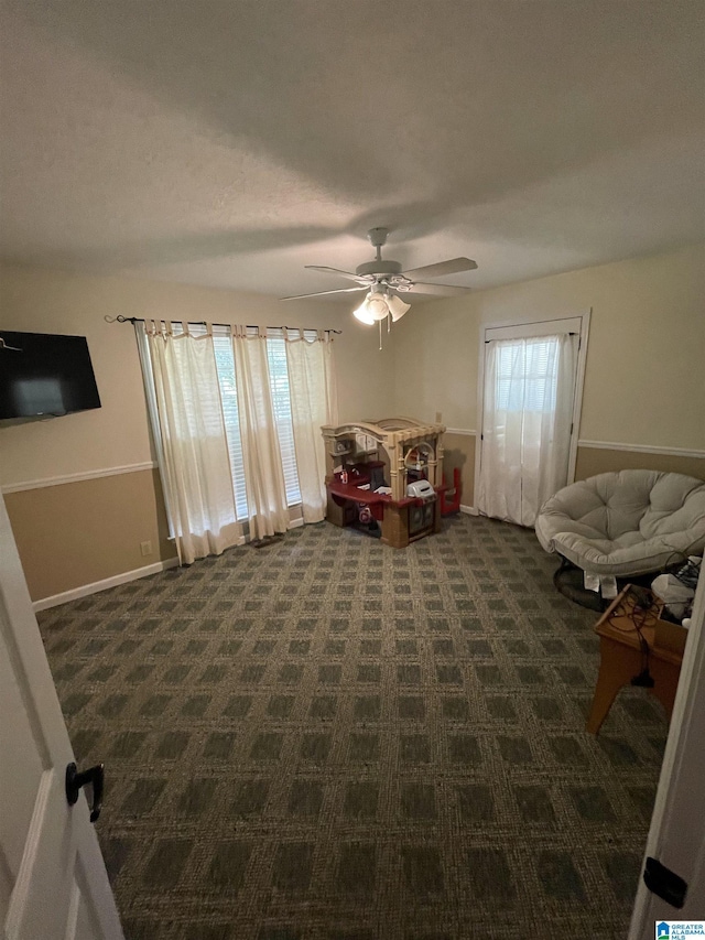 interior space with dark carpet and ceiling fan