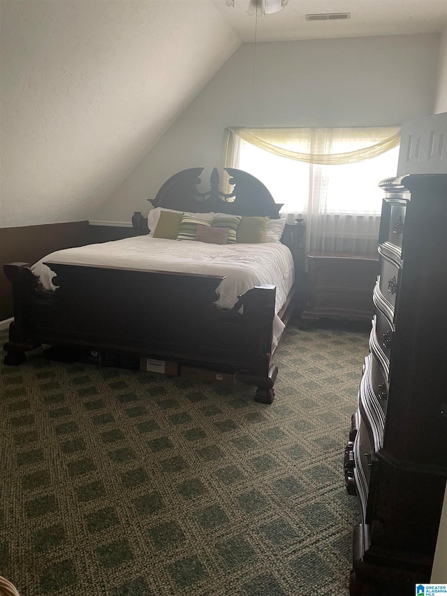 bedroom with dark colored carpet and lofted ceiling