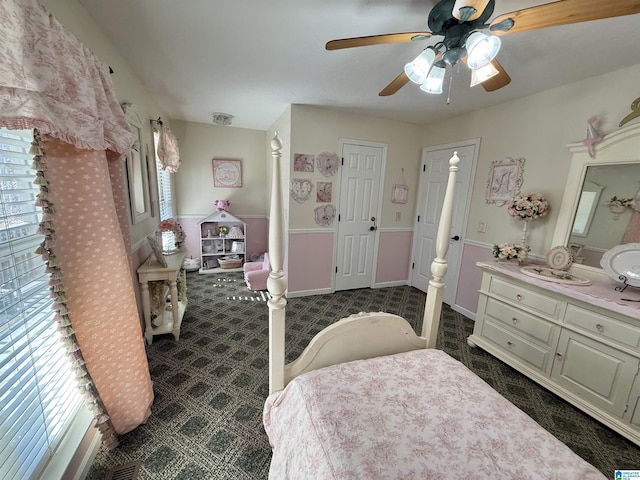 bedroom featuring connected bathroom, ceiling fan, and dark colored carpet