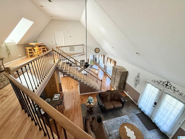 living room featuring vaulted ceiling with skylight, wood-type flooring, and a textured ceiling