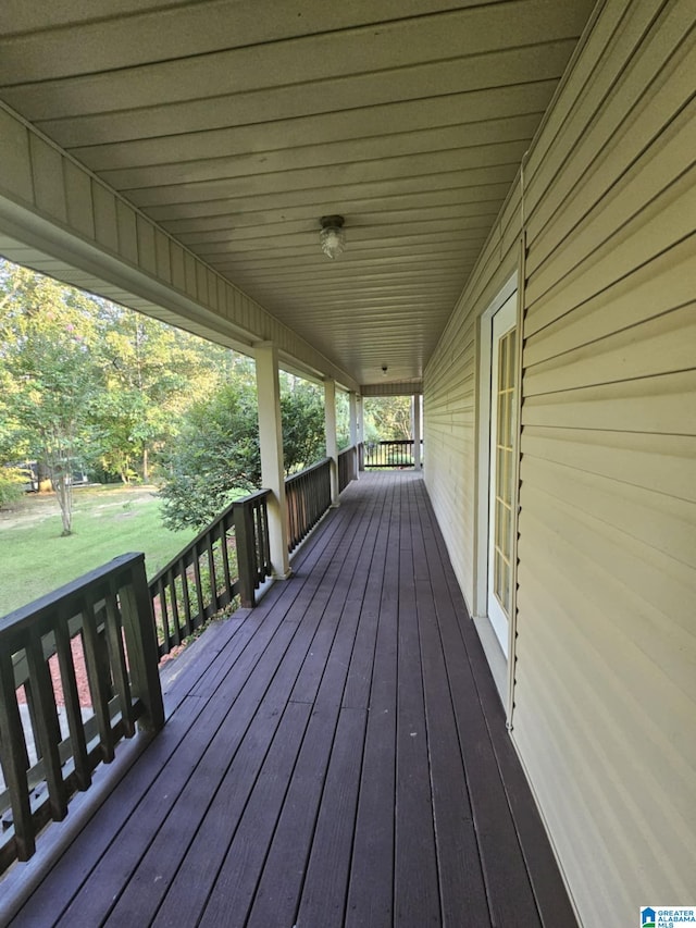 wooden terrace with covered porch and a yard