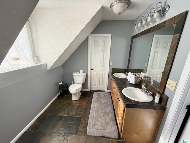 bathroom featuring toilet, a textured ceiling, vaulted ceiling, and vanity