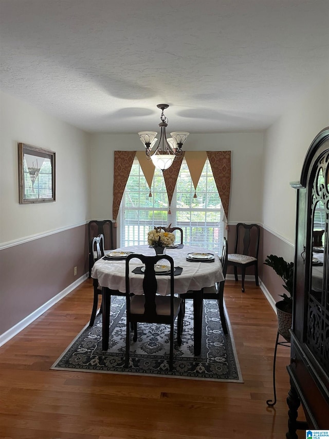 dining area featuring a textured ceiling, dark hardwood / wood-style flooring, and a notable chandelier