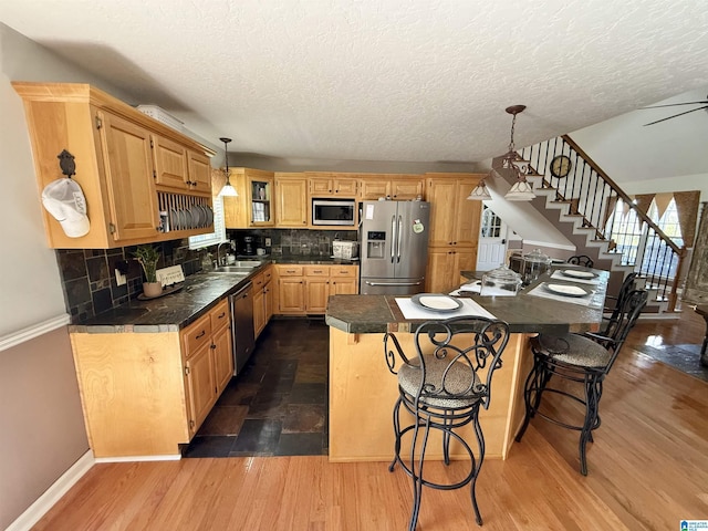 kitchen with appliances with stainless steel finishes, sink, pendant lighting, dark hardwood / wood-style floors, and light brown cabinets