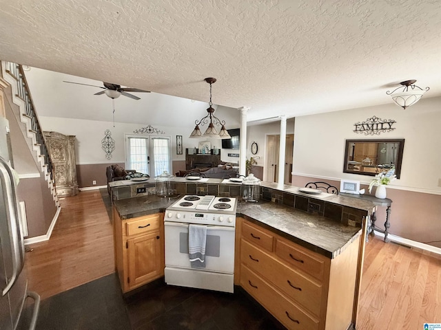 kitchen featuring electric range, ceiling fan, vaulted ceiling, and dark hardwood / wood-style flooring