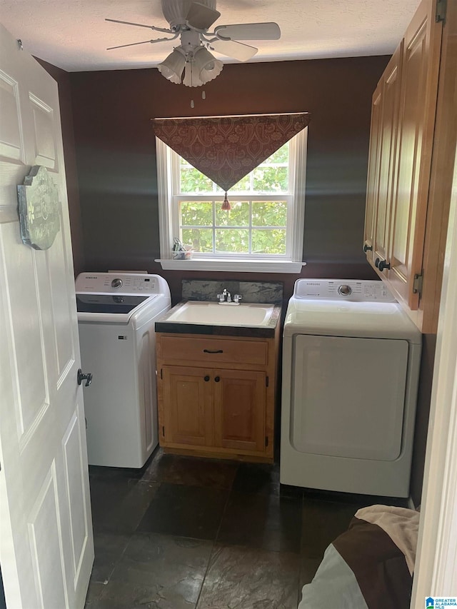 laundry area with ceiling fan, sink, cabinets, washing machine and dryer, and dark tile patterned flooring