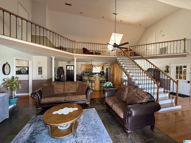 living room featuring a high ceiling, ornate columns, and ceiling fan