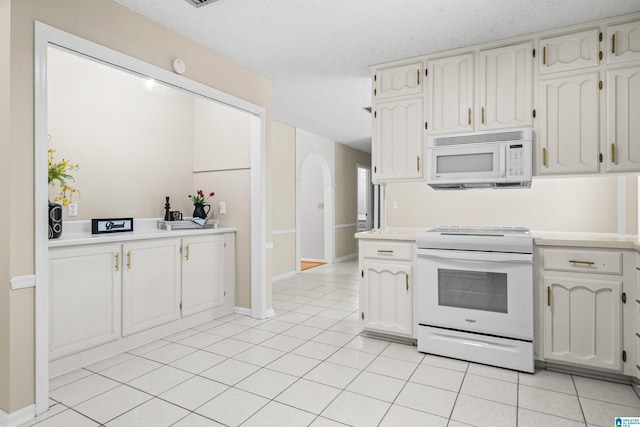 kitchen featuring white cabinetry, white appliances, light tile patterned floors, and a textured ceiling