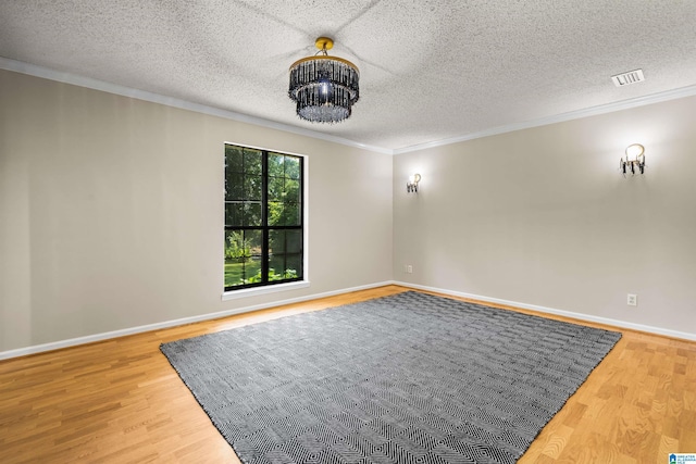 spare room featuring hardwood / wood-style floors, ornamental molding, and a textured ceiling