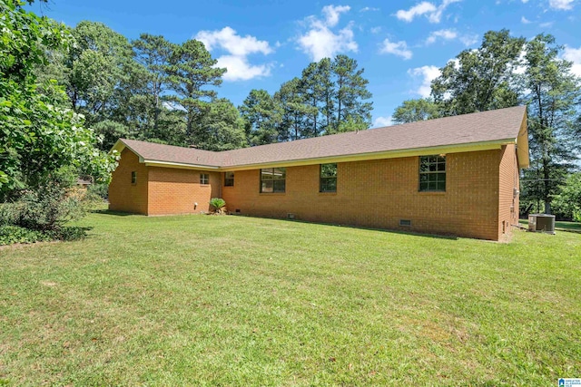 rear view of property featuring central AC unit and a lawn