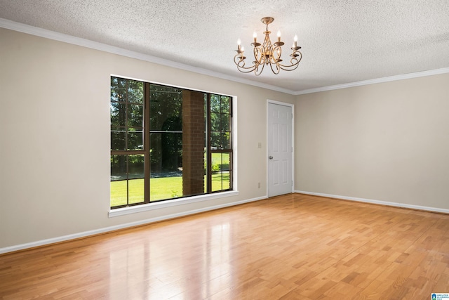 spare room with a textured ceiling, a healthy amount of sunlight, light hardwood / wood-style flooring, and a notable chandelier