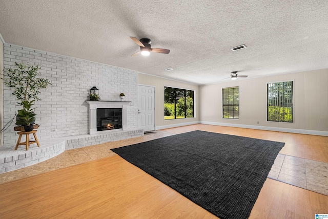 exercise room with a brick fireplace, a textured ceiling, tile patterned floors, and ceiling fan