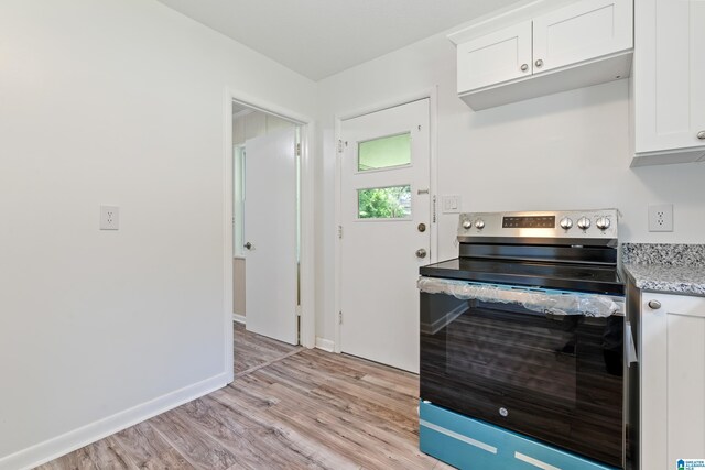 kitchen featuring white cabinets, light stone counters, stainless steel range with electric cooktop, and light wood-type flooring