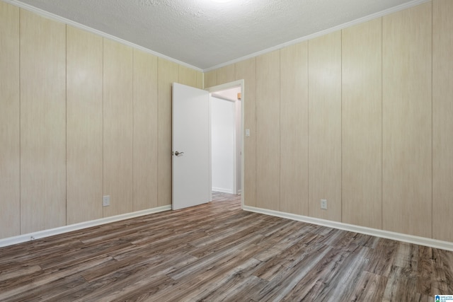 empty room with crown molding, dark hardwood / wood-style flooring, and a textured ceiling