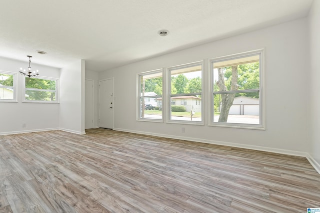 empty room with light hardwood / wood-style floors and a notable chandelier