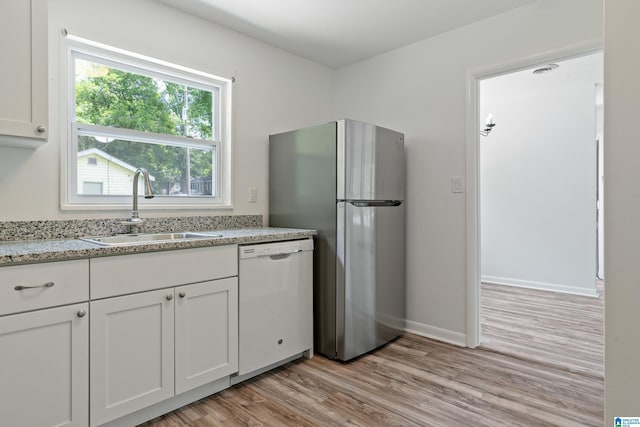 kitchen with stainless steel refrigerator, dishwasher, sink, light hardwood / wood-style floors, and white cabinets