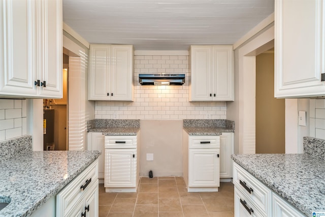 kitchen with light tile patterned floors, backsplash, and light stone counters