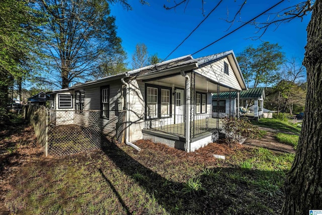 view of side of home featuring covered porch