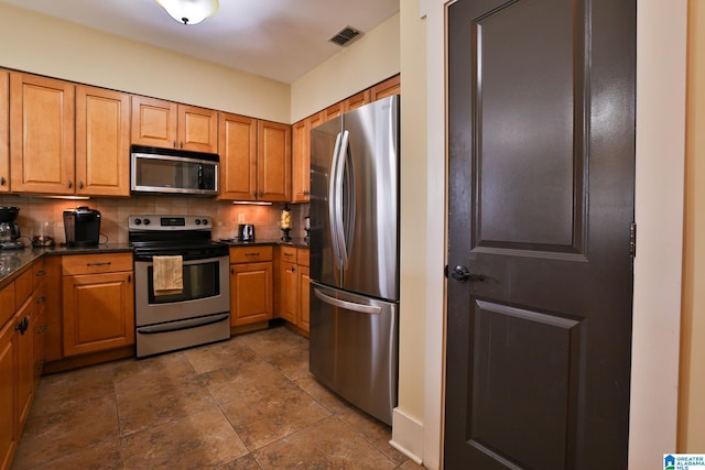 kitchen with appliances with stainless steel finishes, dark countertops, visible vents, and tasteful backsplash