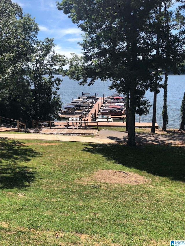 view of community with a dock, a water view, and a lawn