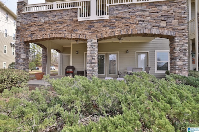 view of exterior entry featuring a patio area, ceiling fan, and stone siding