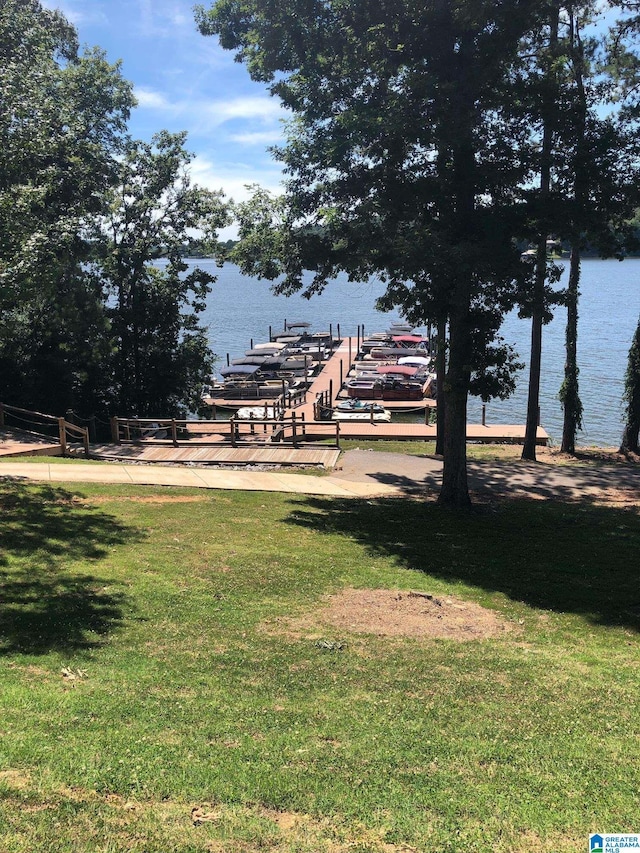 view of community with a water view, a boat dock, and a lawn