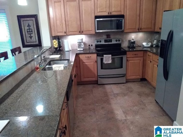 kitchen featuring tasteful backsplash, appliances with stainless steel finishes, dark stone countertops, a peninsula, and a sink