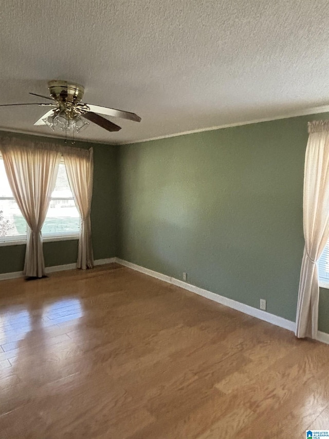 empty room featuring ceiling fan, wood-type flooring, and a textured ceiling